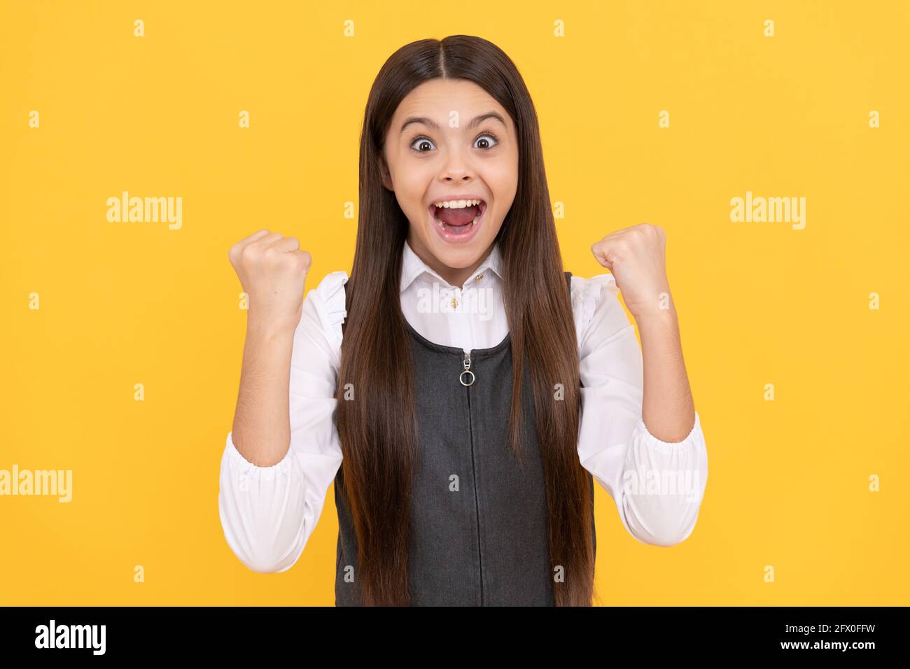 Scholarship winner. Happy teenage winner yellow background. Girl child give winning gesture Stock Photo