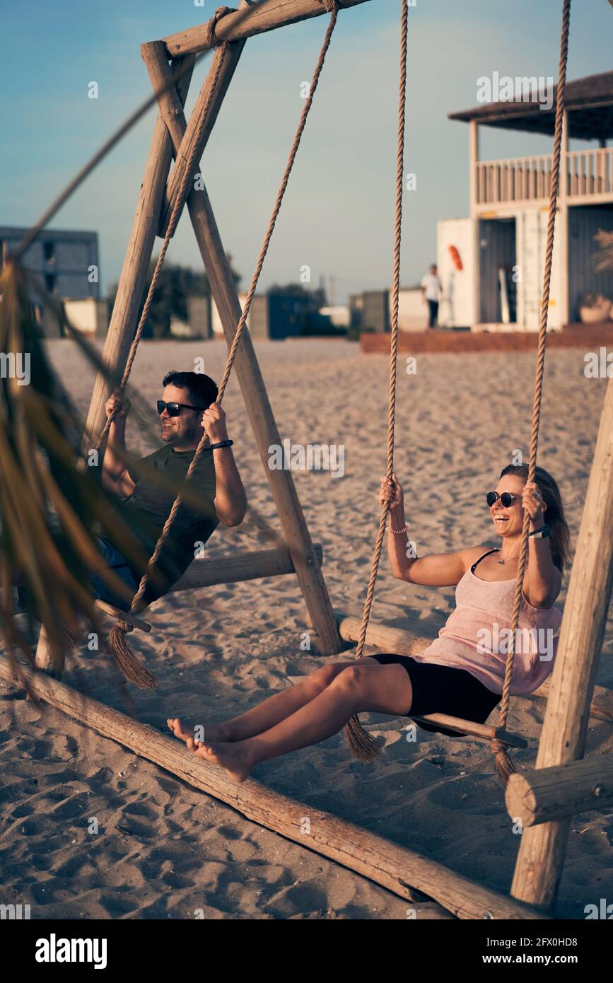 Young attractive couple swinging on seesaw on the beach