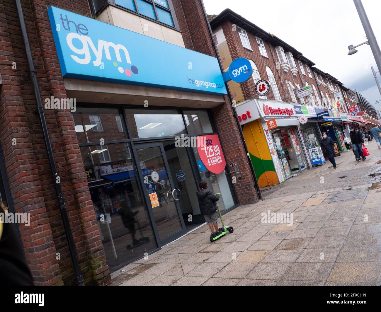 The Gym Group premises Walthamstow High Street, London, with child riding past on scooter Stock Photo