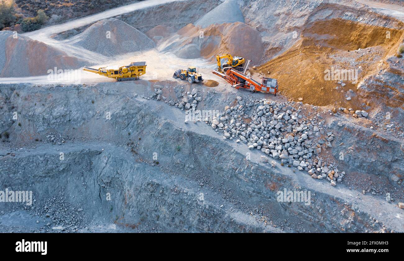 Excavator, bulldozer and conveyor machines on top of stone quarry, aerial view Stock Photo