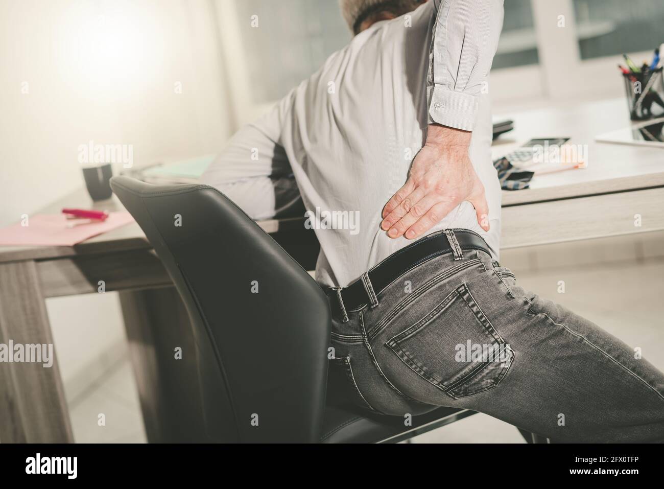 Businessman suffering from back pain in office, light effect Stock ...