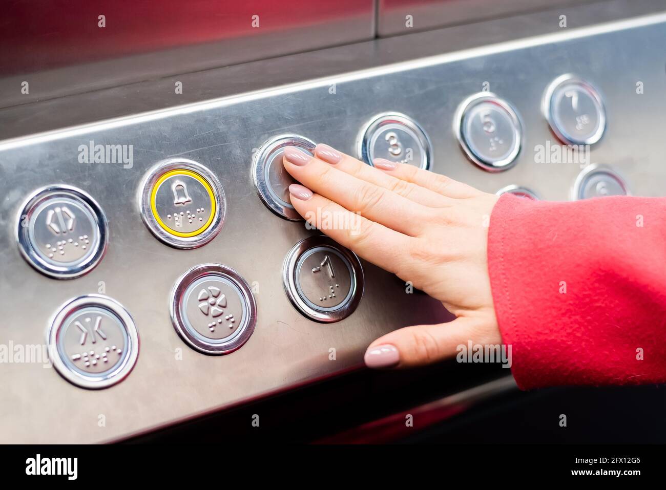Woman pushing a Button in the elevator with Braille code for blind