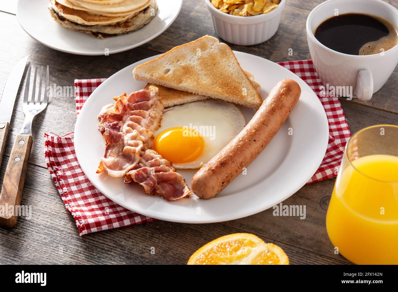 Traditional American breakfast with fried egg,toast,bacon and sausage on wooden table Stock Photo
