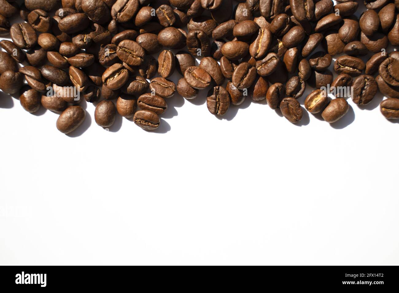 Isolated roasted coffee beans in harsh light. White background, top ...
