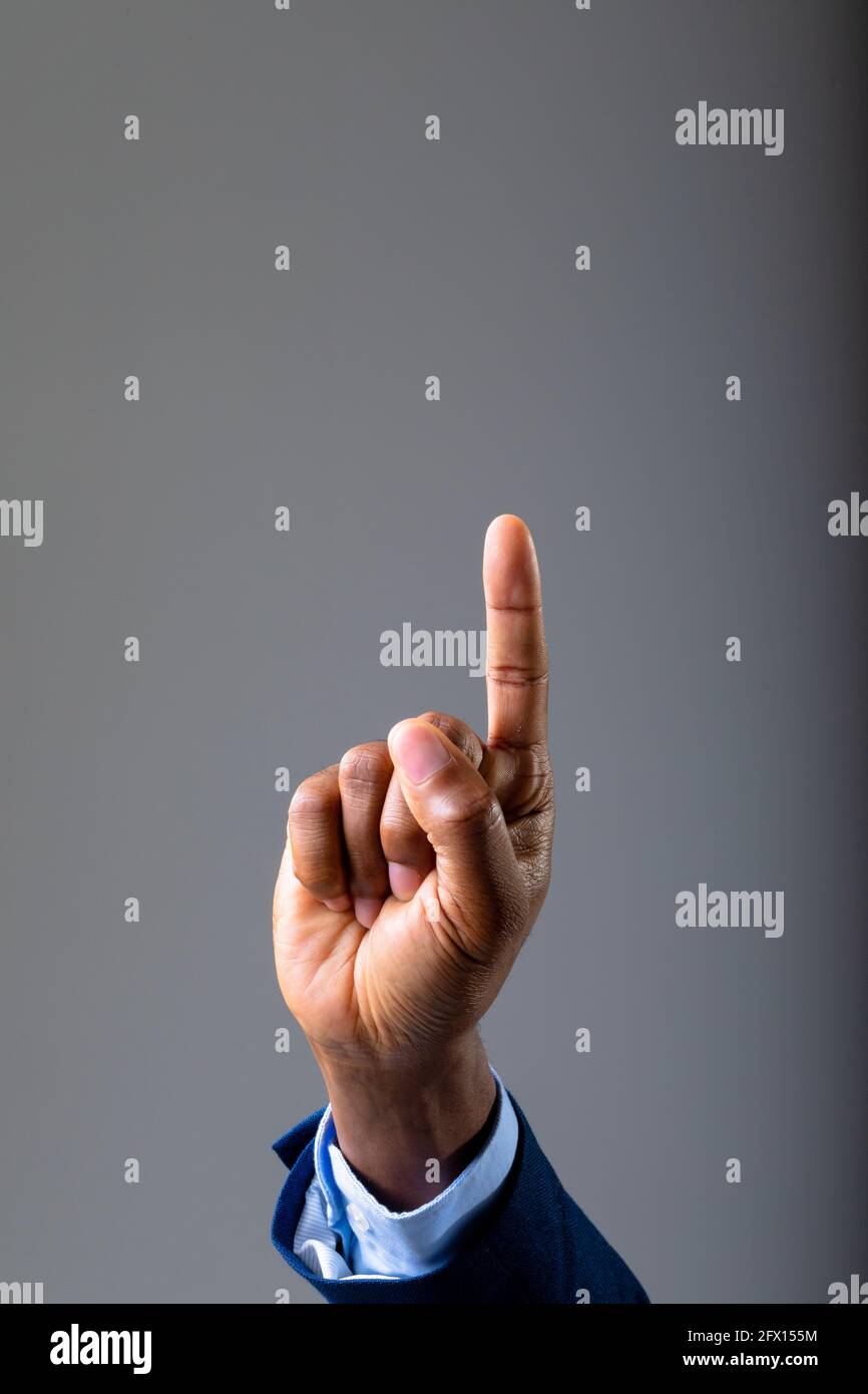 Close up of hand of businessman touching invisible screen against grey background Stock Photo