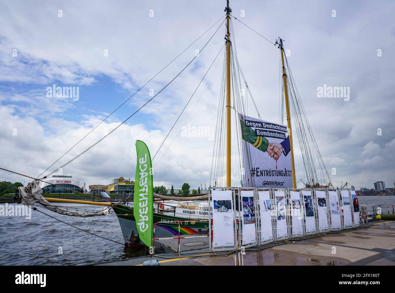 Hamburg, Germany. 25th May, 2021. The Greenpeace ship Beluga II, on which a  banner with the words "Against Germany's bomb deals. #EntrüstungJetzt", is  moored at the Überseebrücke in the harbour. The ship