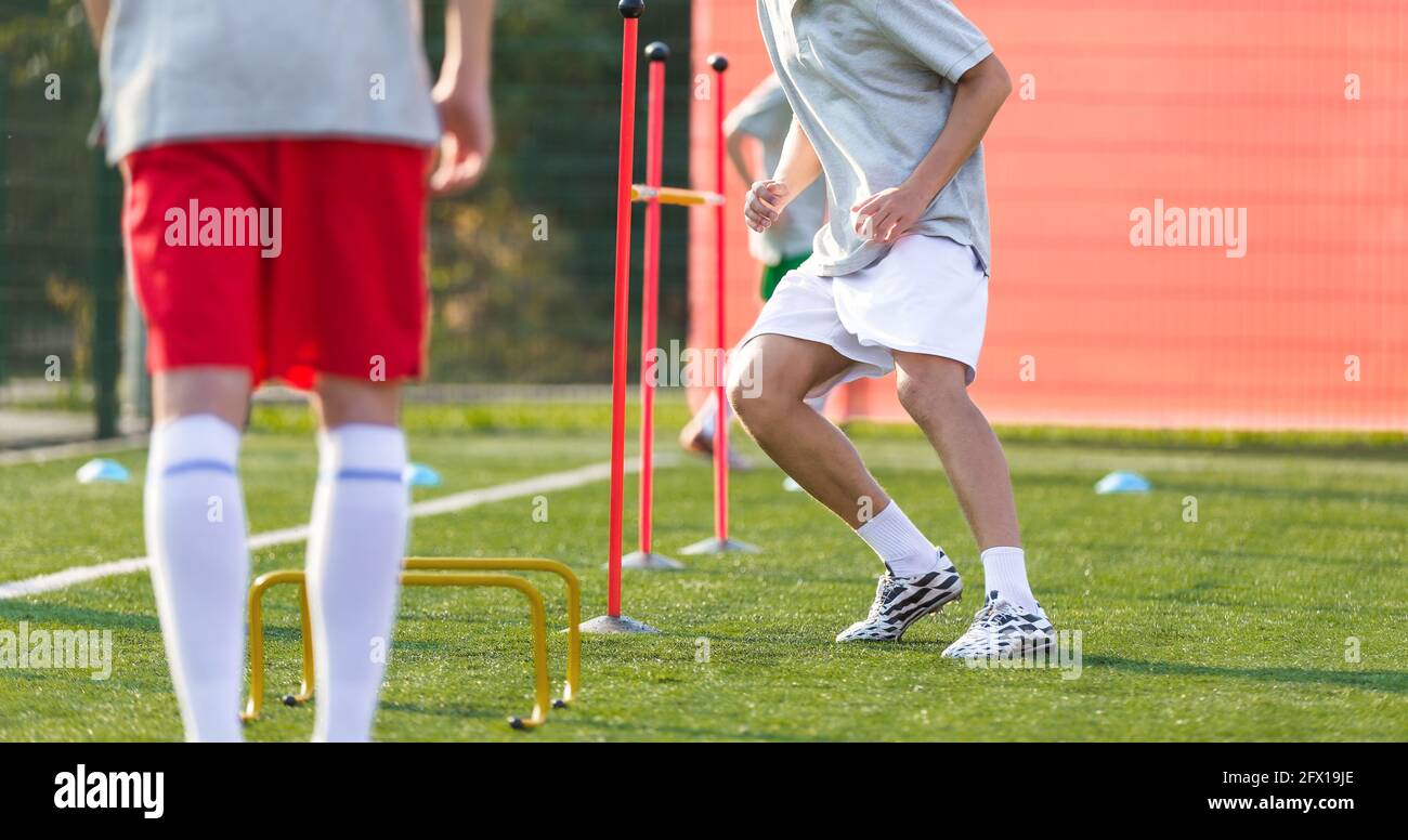 Teenage Football Players on Training Camp. Young Boys Running Slalom Track Between Training Poles and Jumping Over Hurdles. Soccer Training Equipment Stock Photo