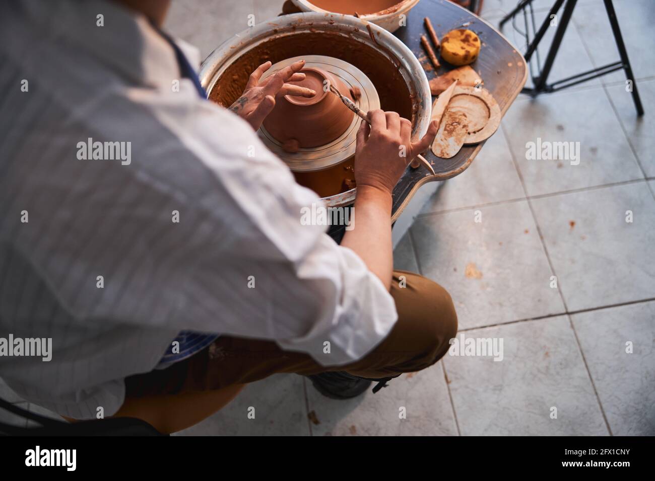 Craftsman smoothing bottom of bowl with tool and finger Stock Photo