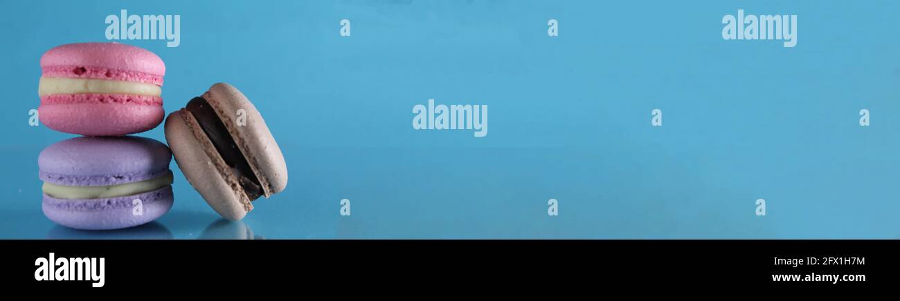 three macaroons lie triangle on a blue background with a place for text and copyspace. Stock Photo