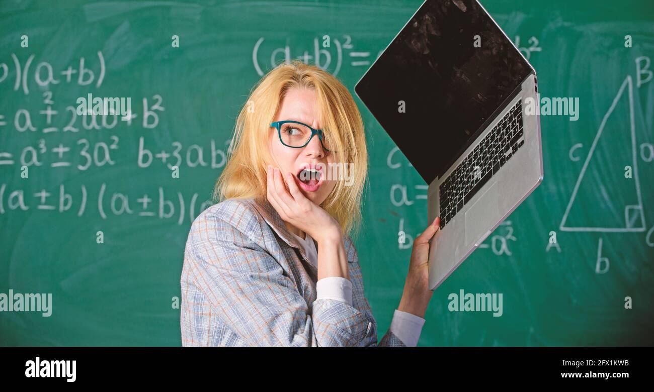 Teacher woman raising laptop above herself ready to destroy. Working conditions of teachers causes nervous disease. Overstrain of the nervous system Stock Photo