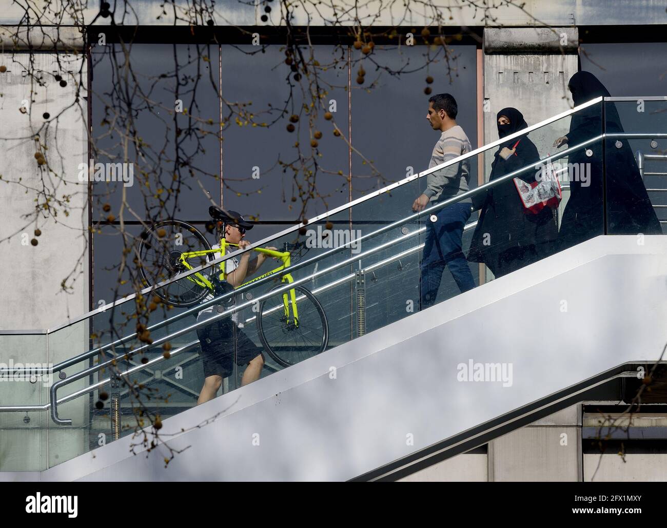 London, England, UK. Muslim family passing as man carying his bike up steps to the Golden Jubilee Bridge in Northumberland Avenue Stock Photo