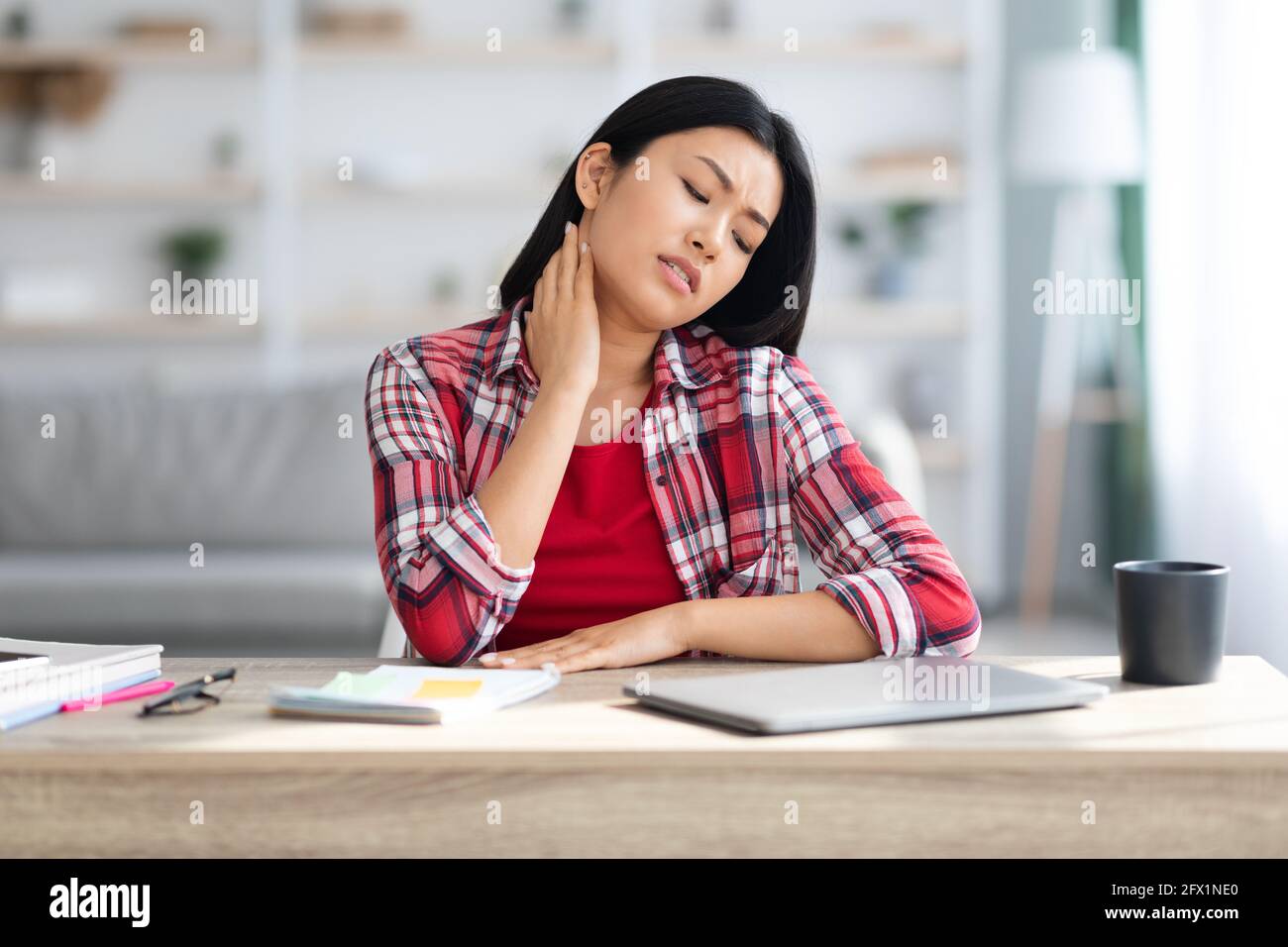 Neck Pain. Tired Asian Female Massaging Inflamed Neck After Working On Laptop Stock Photo