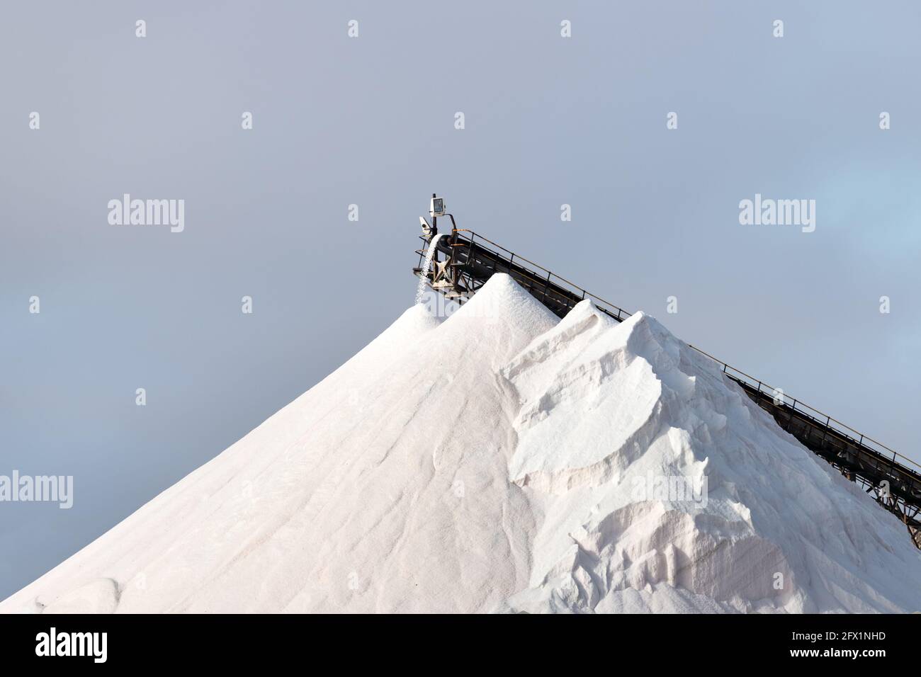 Huge pile of salt against the blue sky. Marine salt production Stock Photo
