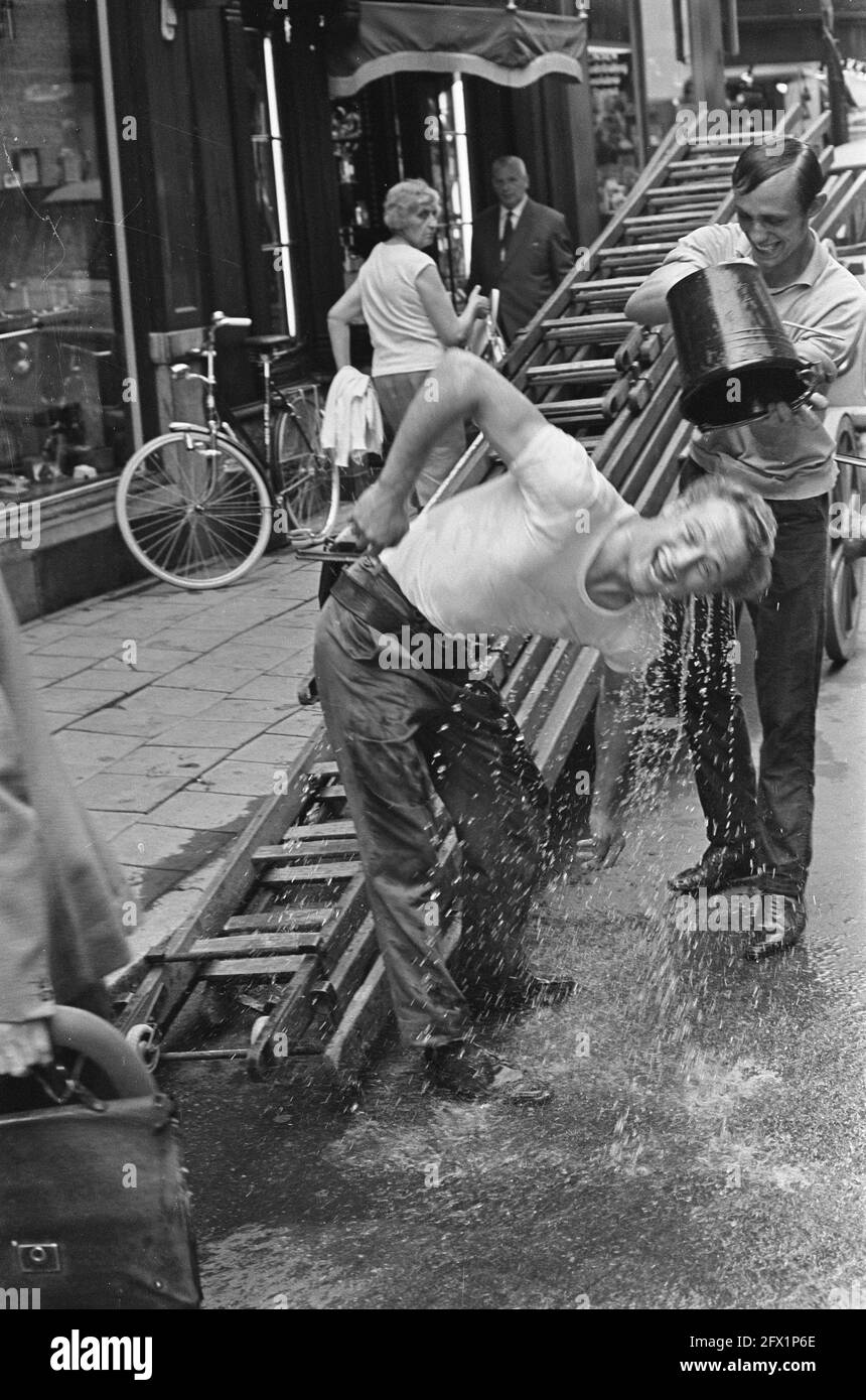 Heat. Glass washer gets bucket of water over him, July 15, 1967, window