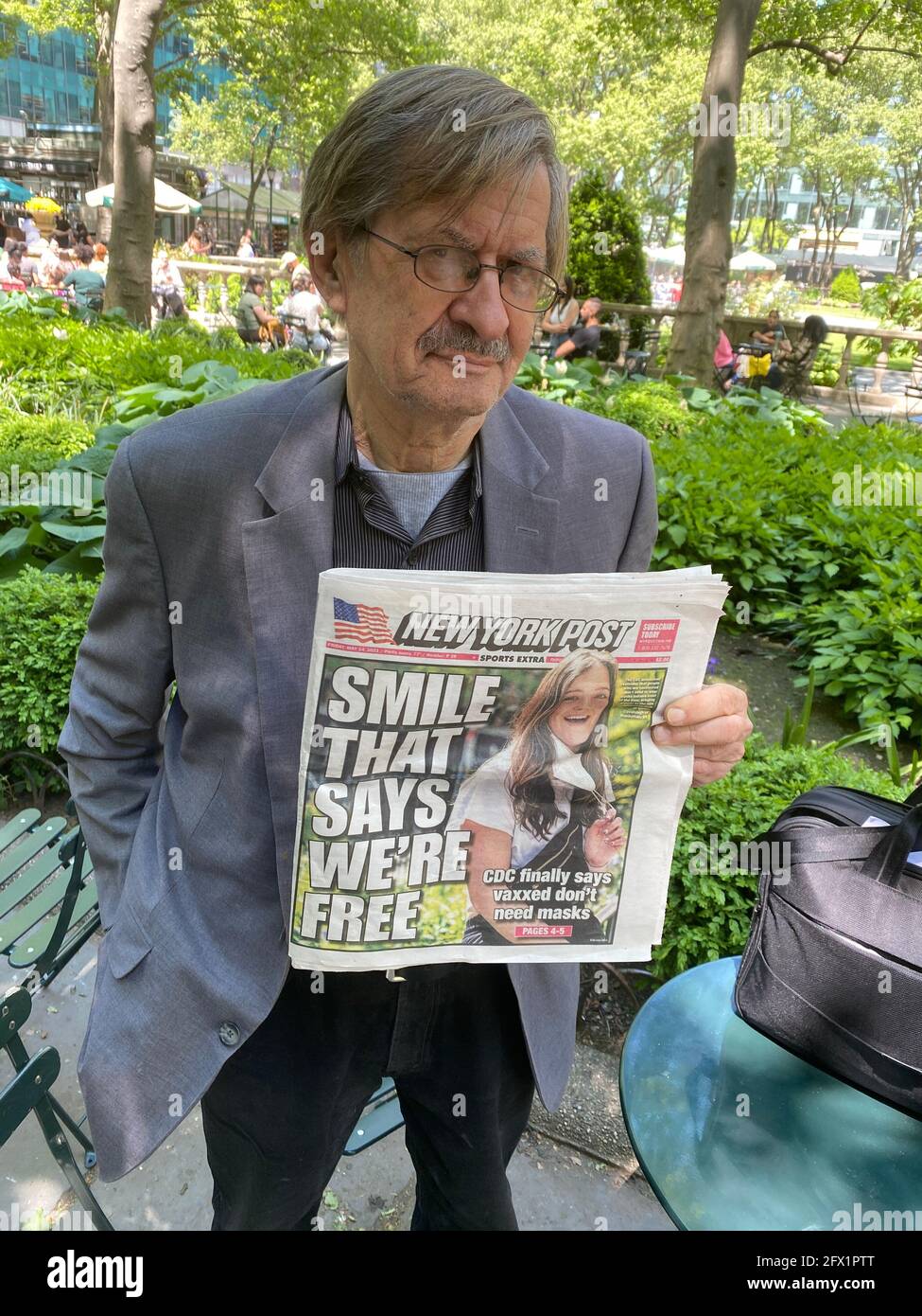 Man shows cover of the New York Post, breaking the news of  the 'take off your mask'  decision  guidelines in the USA by the CDC for vaccinated people. Stock Photo