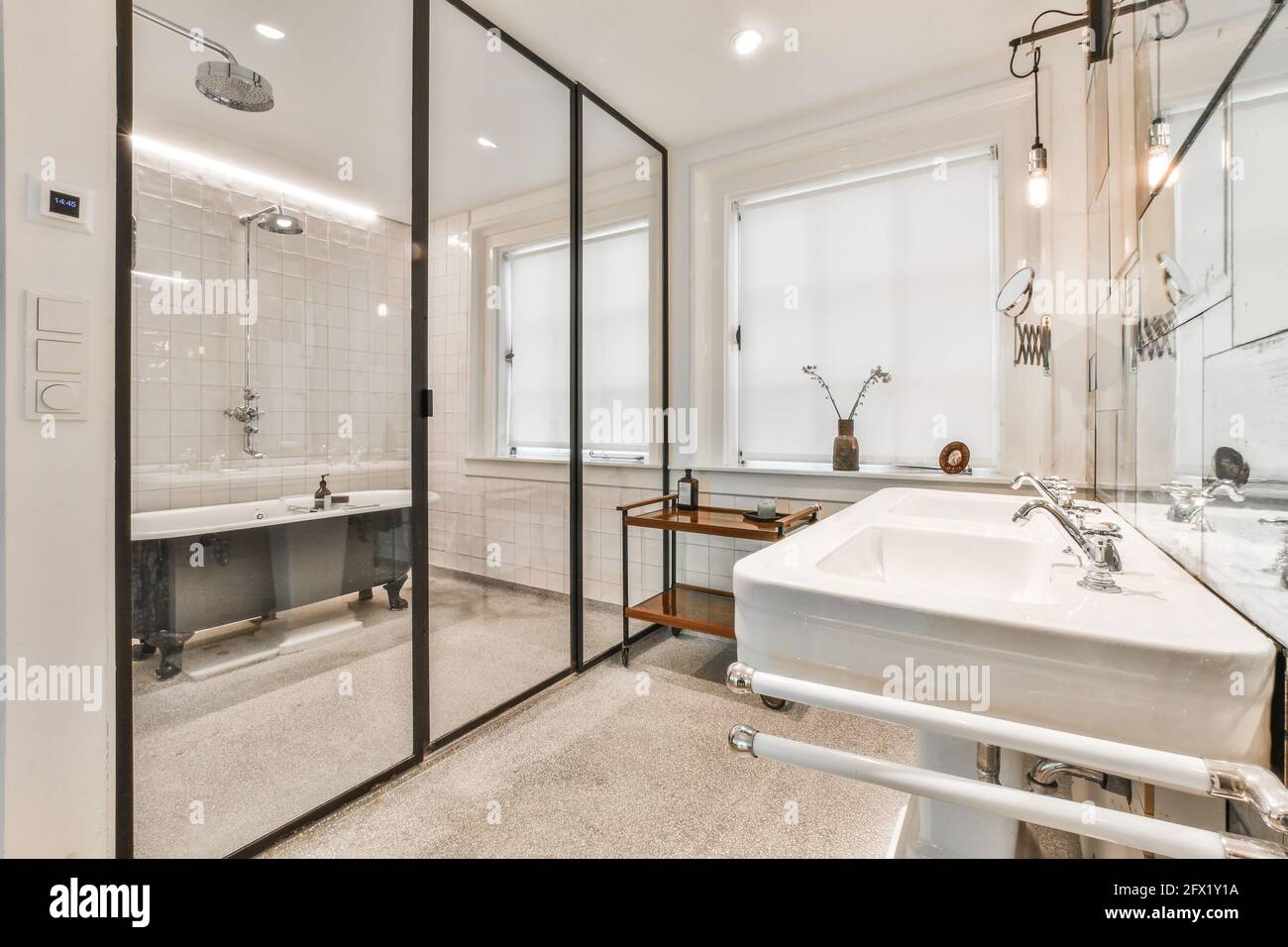Glass wall in modern white bathroom with black soaker tub and small