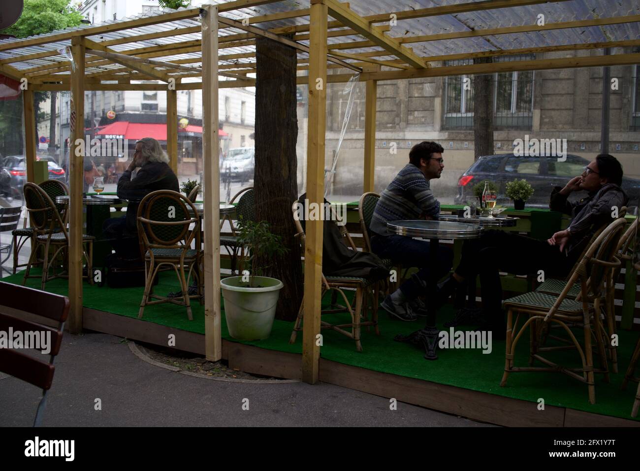 Parisians enjoy sitting at a temporary cafe terrace, built to enable customers to drink outside after Covid-19 restrictions were lifted in Paris in May 2021 - Le Montmartre Café, Rue Custine, 75018, Paris, France Stock Photo