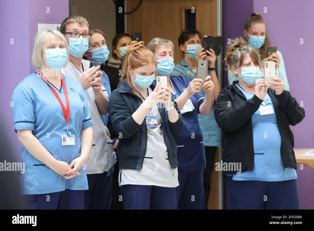NHS staff take photos on their mobile phones as the Duke and Duchess of