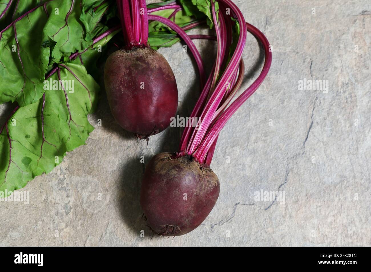 Red Beet Root With Leaves on stone table Stock Photo