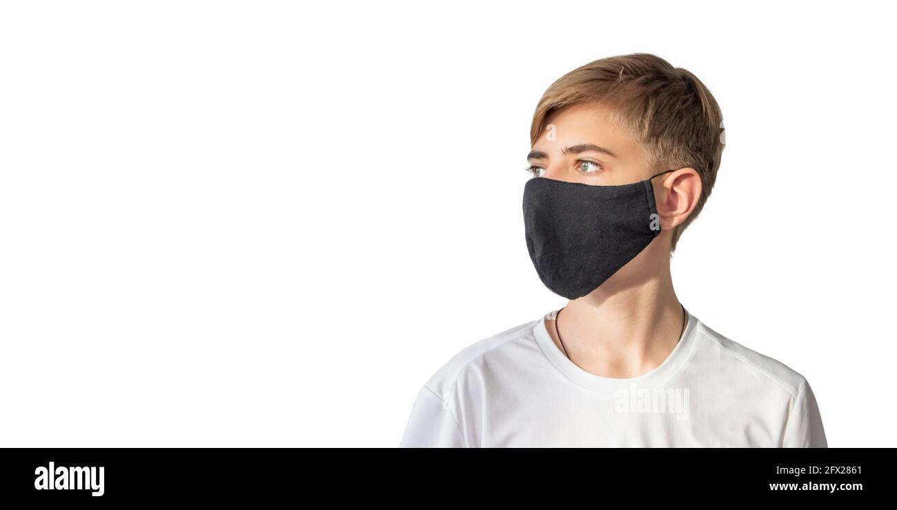 Portrait of a teenage boy in a surgical medical protective black mask on a white background, copy space Stock Photo