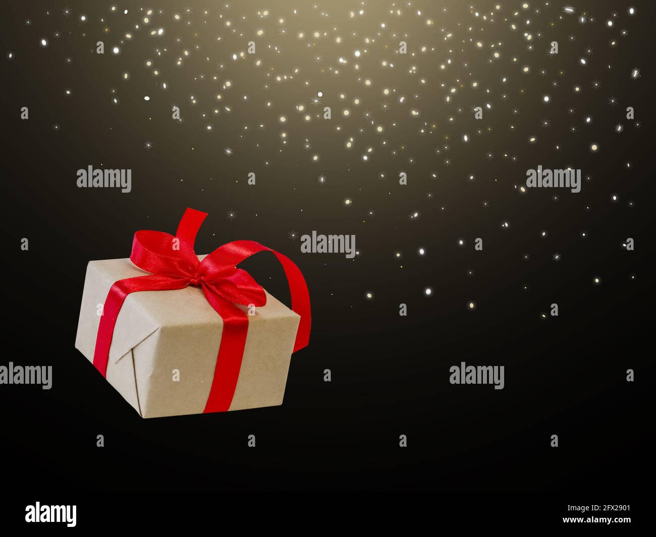 Christmas snow falling on a gift box with a red bow Stock Photo - Alamy