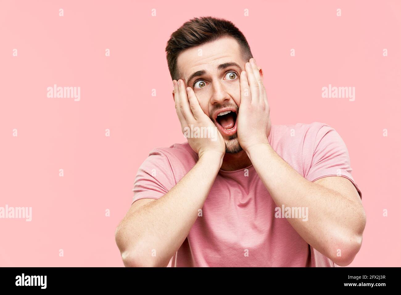 Close up portrait of shocked excited scared man with open mouth panicking over pink background. Face expression, omg, emotions concept. Stock Photo