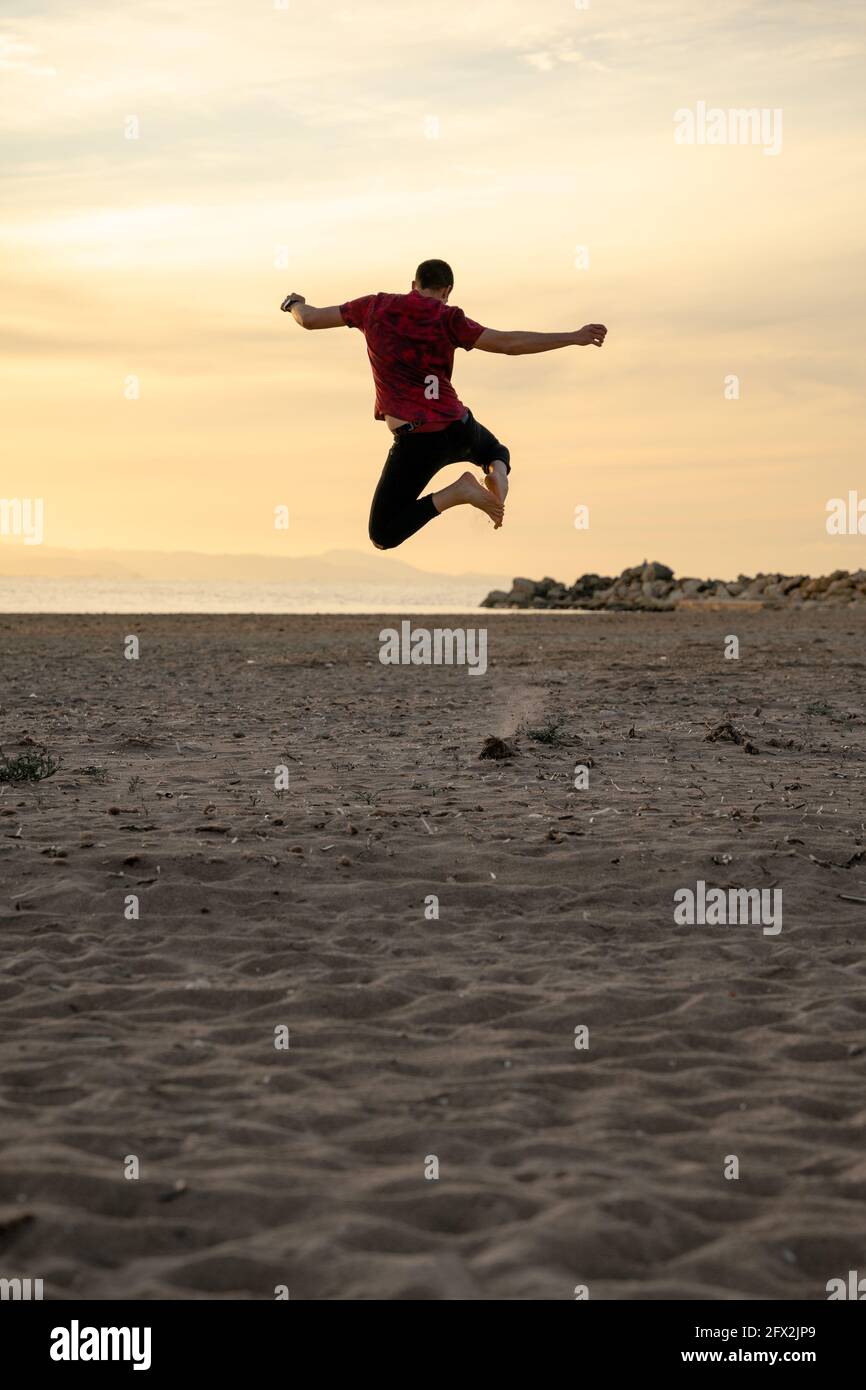 Man jumping for joy on the beach. It's getting dark. they jump on the sand. He jumps and puts