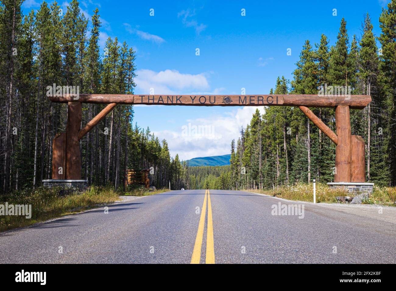BANFF, ALBERTA, CANADA - 2016 SEPT 8: Sign on the road between Banff and Lake Louise saying Thank You and Merci on a wooden beam gate, road with two y Stock Photo