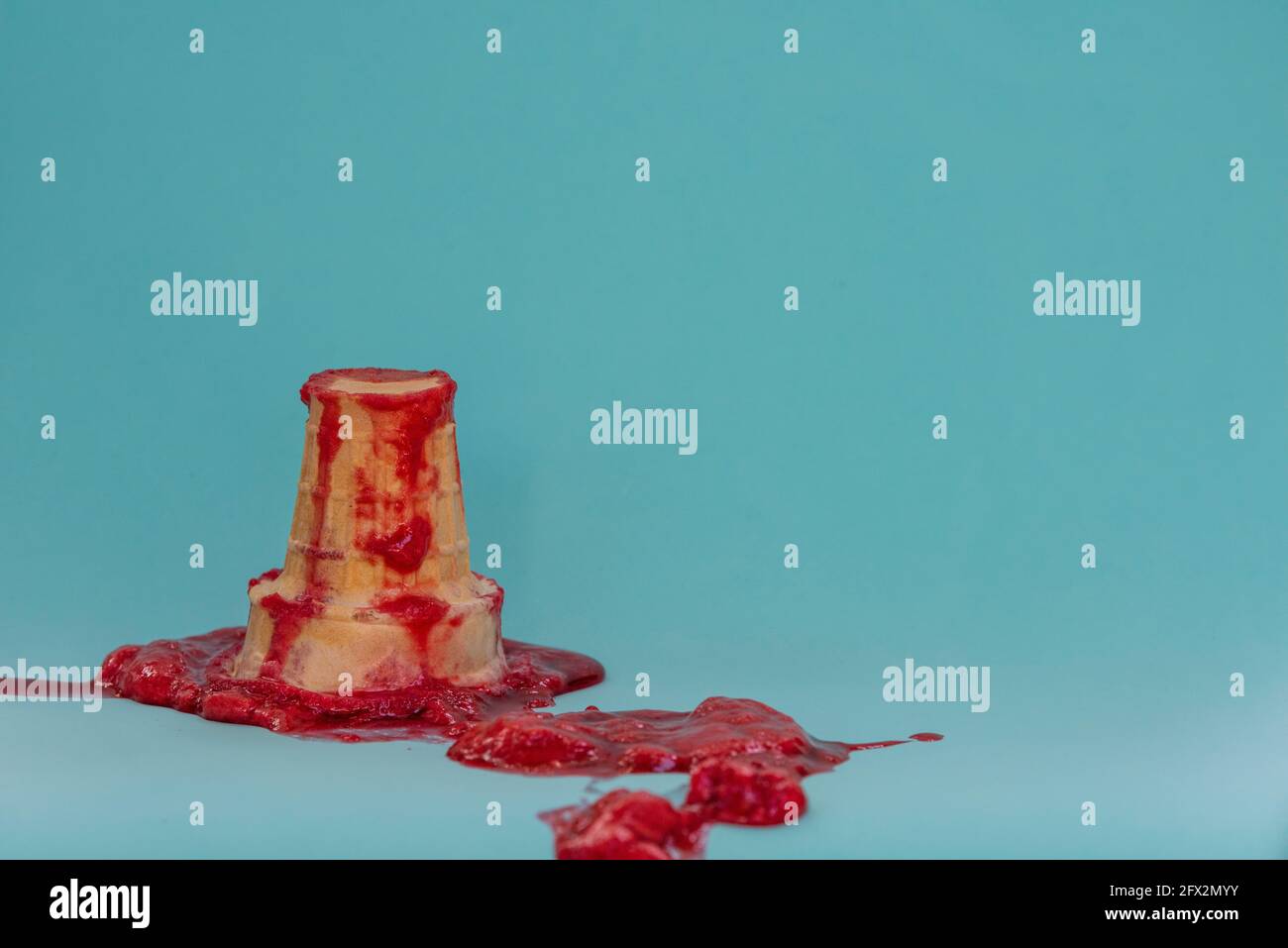 A melted ice cream cone is spilled and splattered on a blue background. Failure concept. Stock Photo
