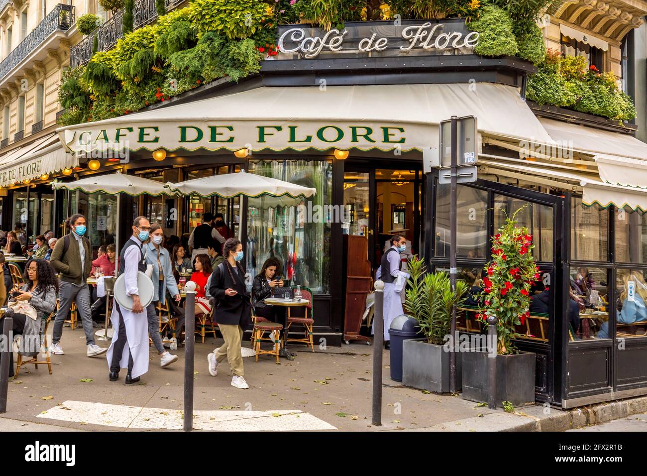 Paris, France - May 19, 2021: Day after lockdown due to covid-19 in a famous Parisian cafe. 2 waiters wear surgical masks Stock Photo