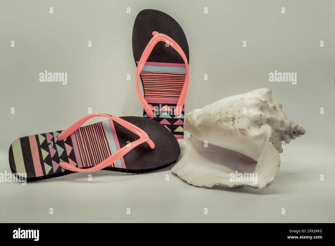 summer flip flops and sea shell composition in green background with ...