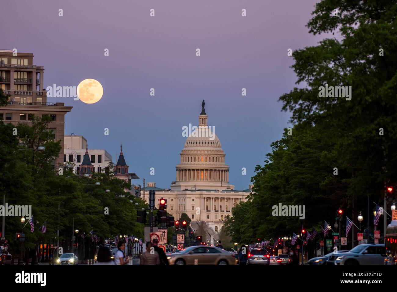 The last rays of the sun set on the United States Capitol Building as the moon rises over Washington, D.C. Stock Photo