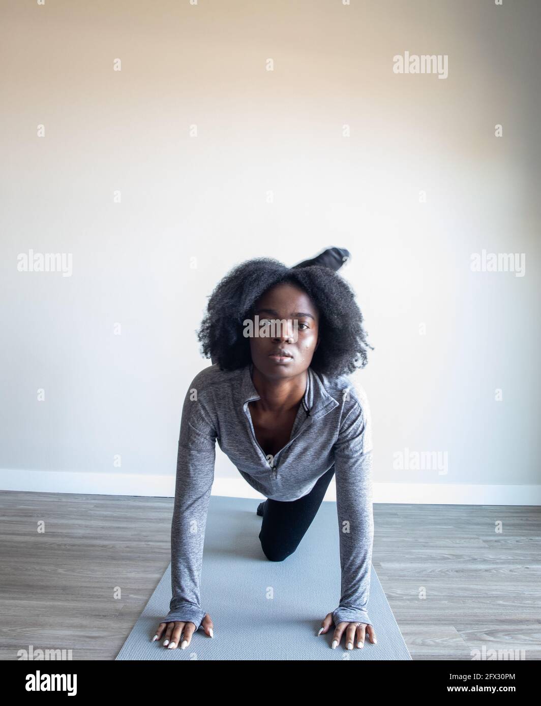 Young woman doing yoga exercise on yoga mat in home studio, one person, close up, natural hair, black woman, african american Stock Photo