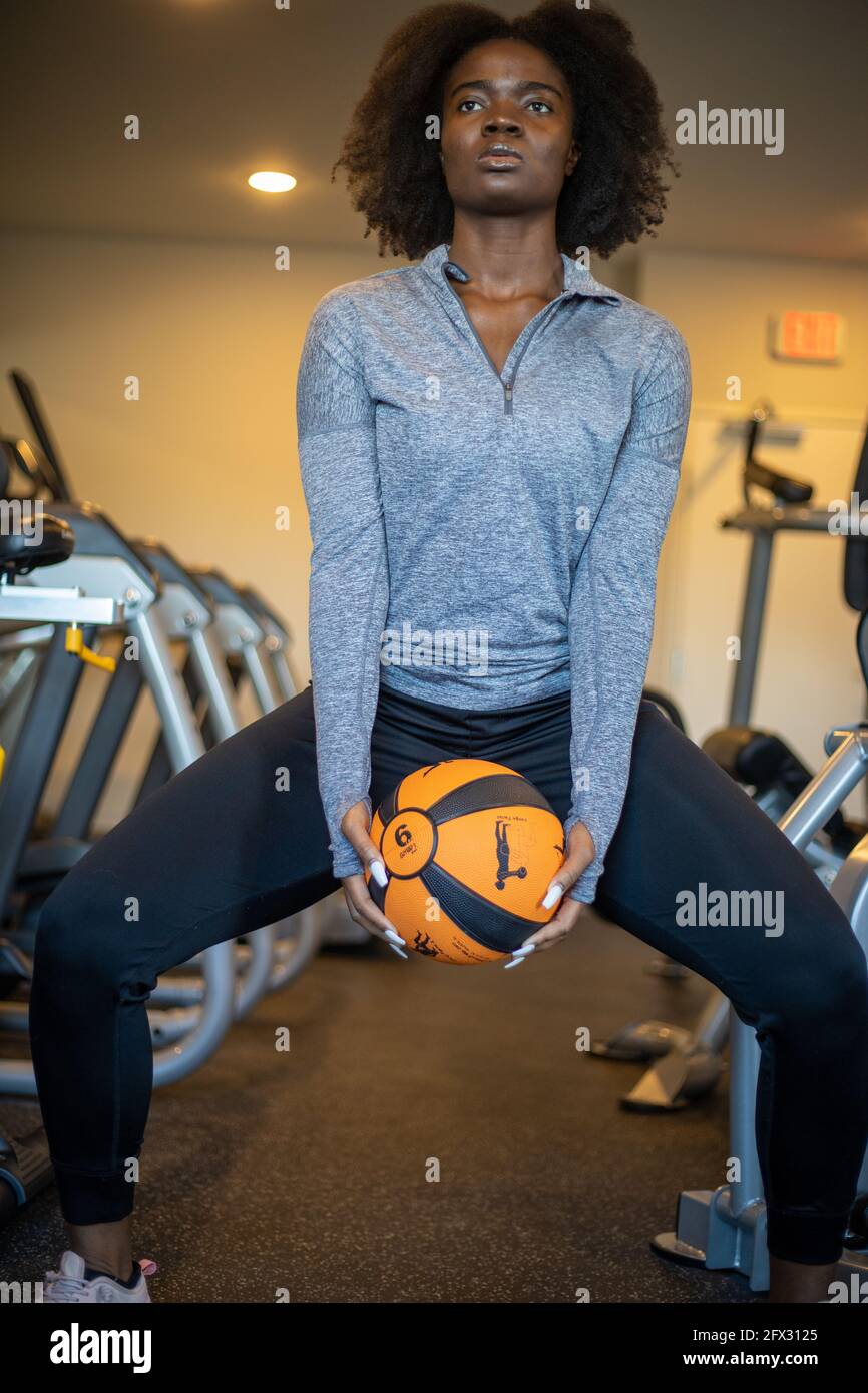 Slim sporty girl exercising with fitness ball in fitness gym. one person, close up portrait, african american, natural hair model, black model, liftin Stock Photo