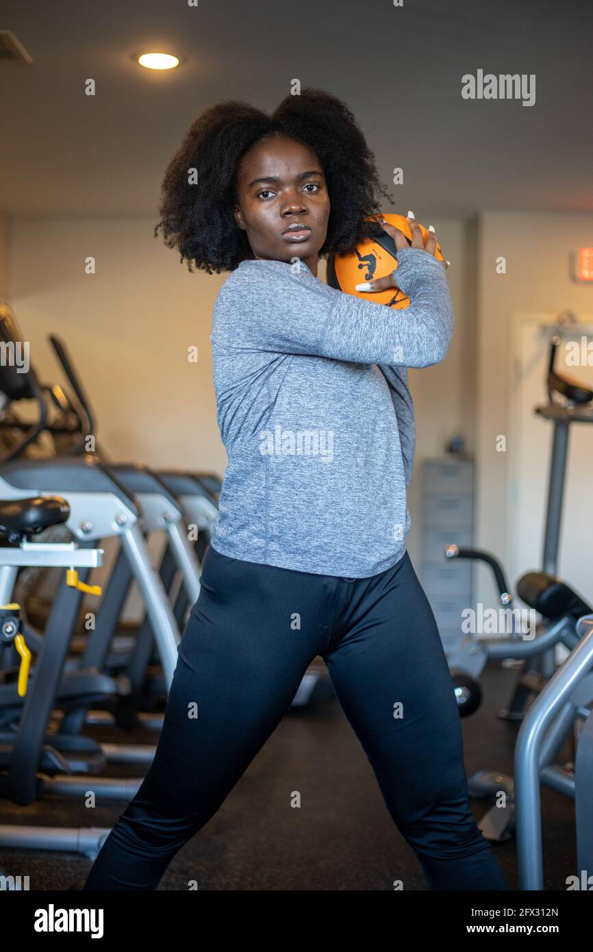 Fit sporty girl exercising with fitness ball, lifting, one person, close up, black woman, african american, background, fitness center Stock Photo