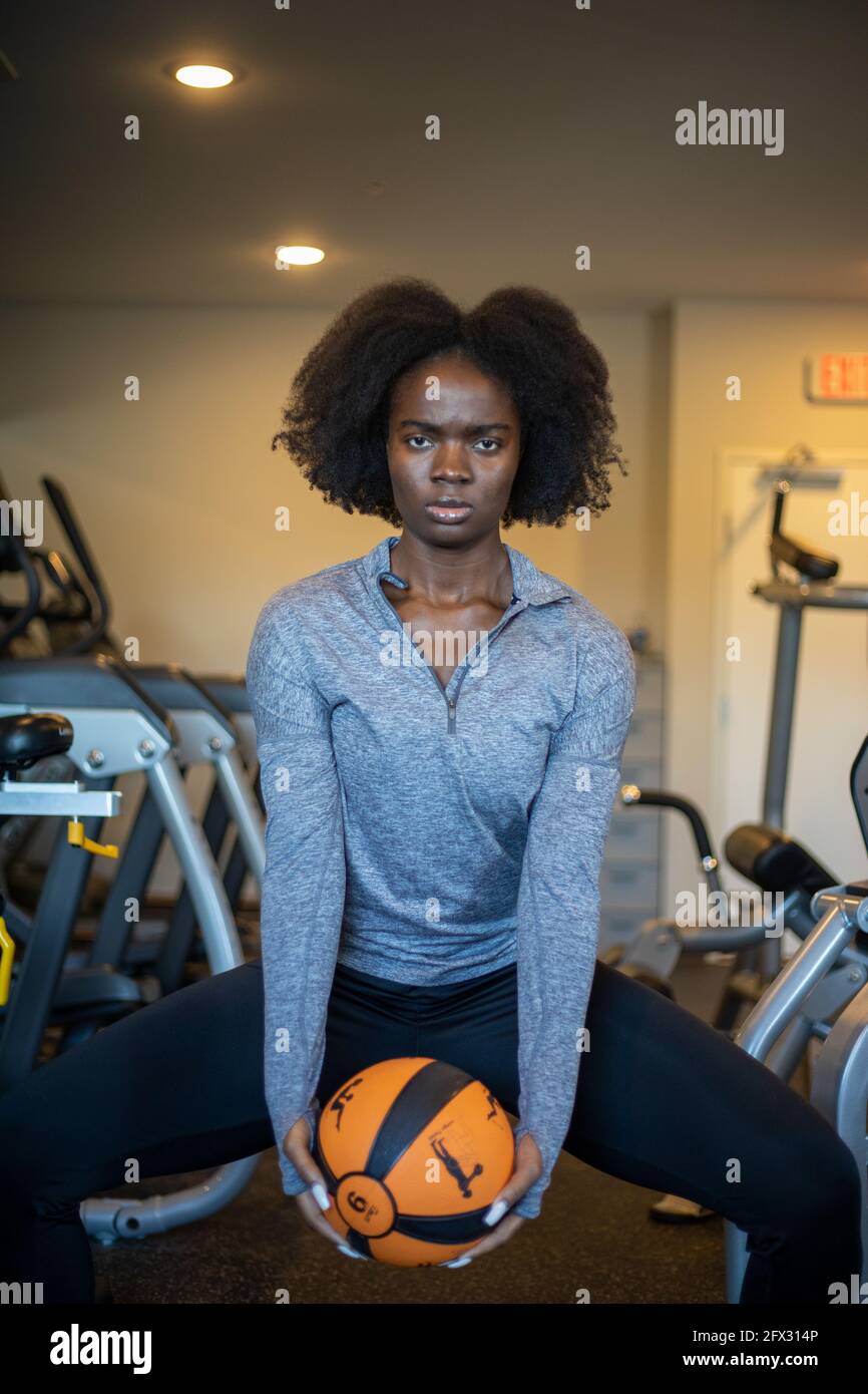 young sporty girl doing exercise with fitness ball, one person, natural hair, black model, close up, background, african american,lifting weight ball Stock Photo