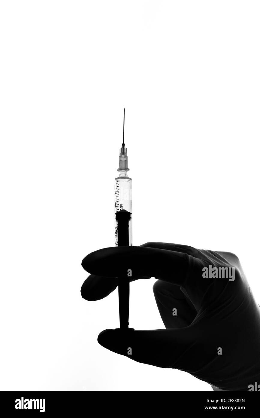 Syringe on doctor's hand wearing white gloves stock image Stock Photo