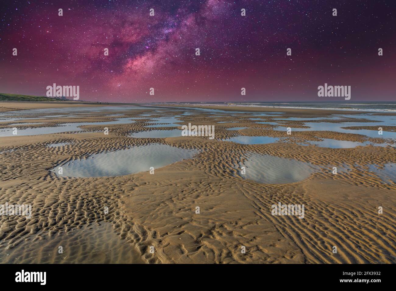 Night scene with clear starry sky over deserted coastal landscape with dunes, sea and beach with lagging saltwater lakes at low tide Stock Photo