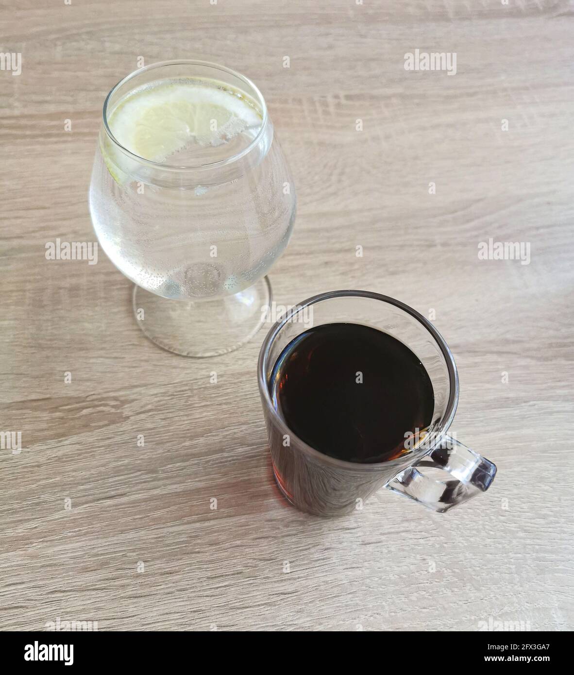 Coffee and water in a glass with lemon on a wooden table Stock Photo