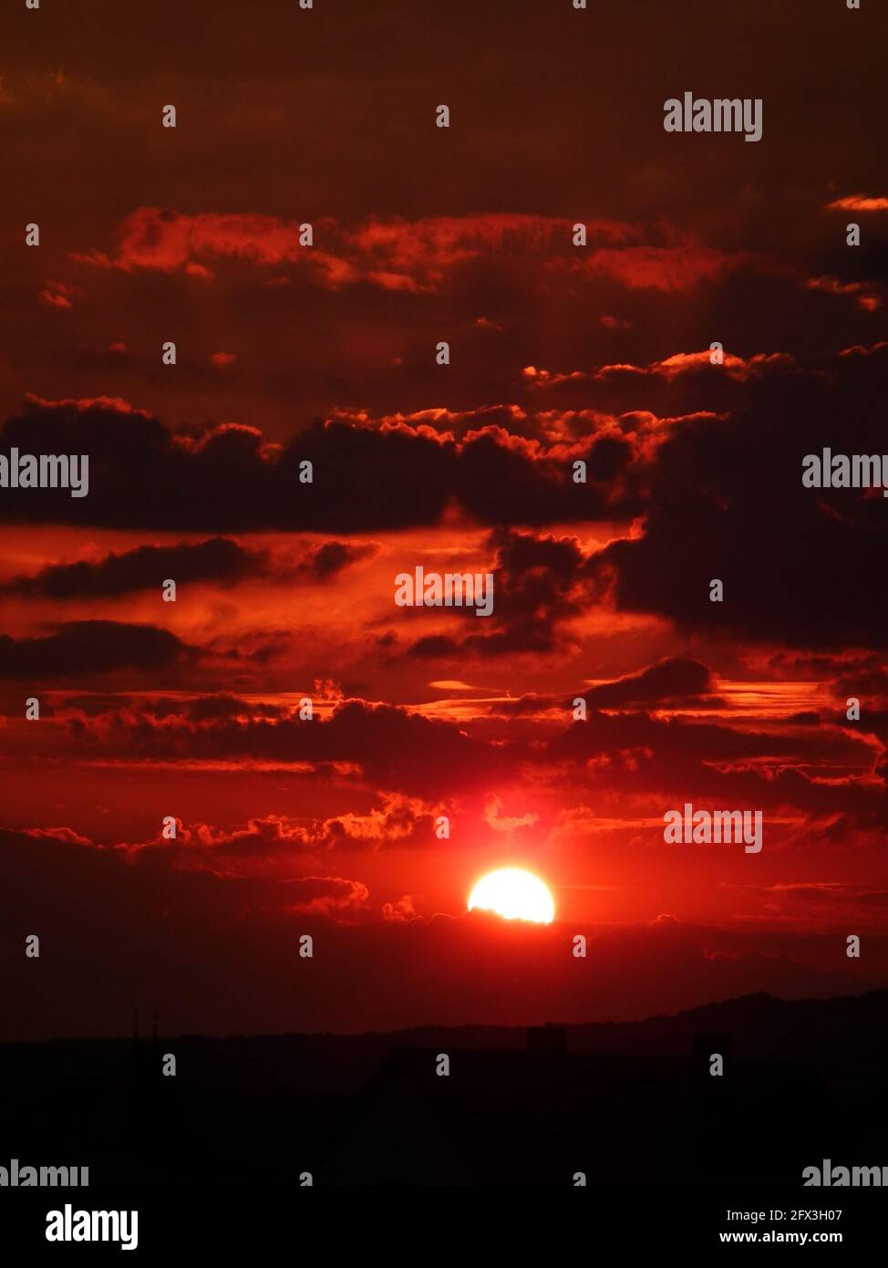 Red Sky Dark Clouds Sun Peaking Stock Photo