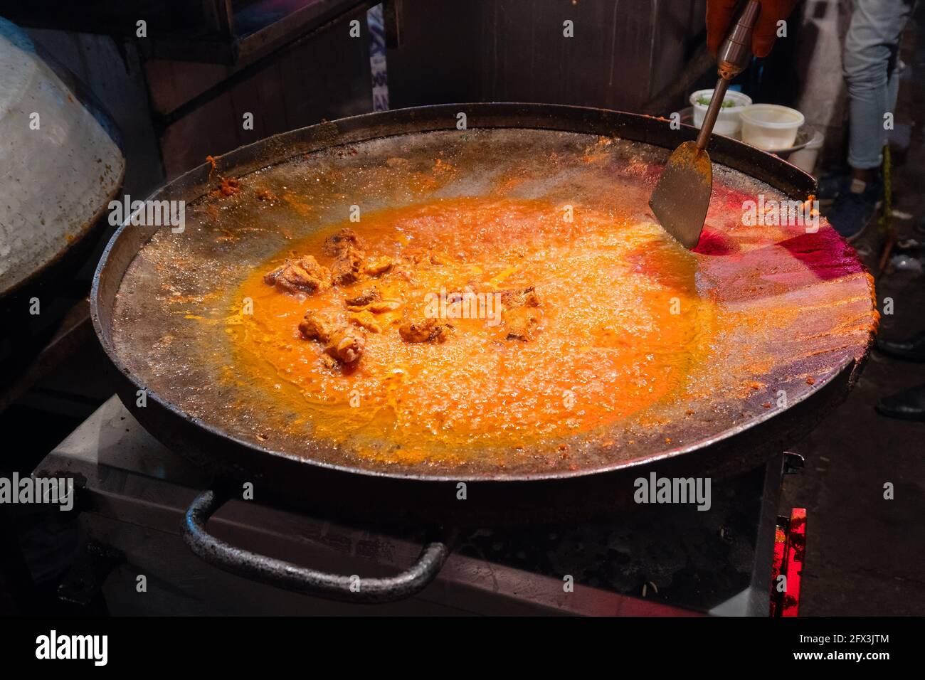Spicy chicken curry is being prepared with heat at evening for sale as street food in Old Delhi market. The place is very famous for spicy Indian non Stock Photo