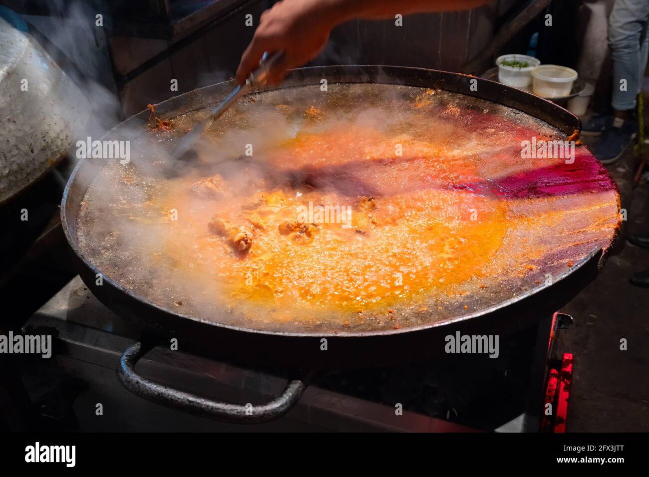 Spicy chicken curry is being prepared with heat at evening for sale as street food in Old Delhi market. The place is very famous for spicy Indian non Stock Photo