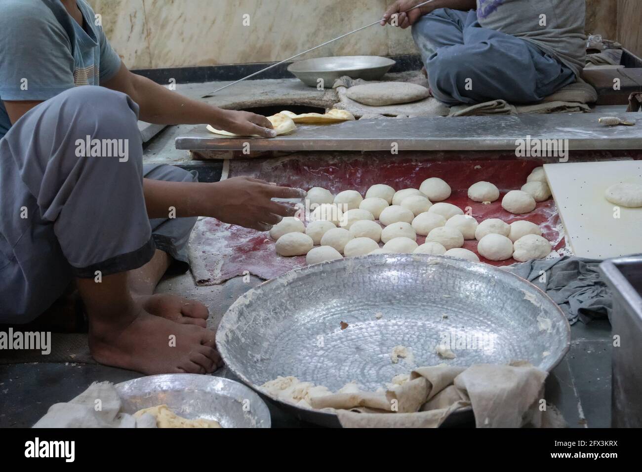Male persons preparing naan by hands. Naan is a leavened, oven-baked flatbread found in the cuisines mainly of West Asia, Central Asia, Southeast Asia Stock Photo