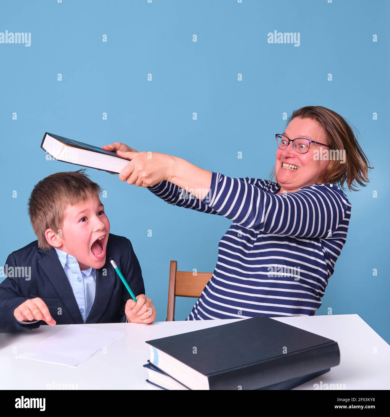 https://c8.alamy.com/comp/2FX3KY8/angry-mom-hits-schoolboy-boy-at-school-desk-with-book-blue-background-2FX3KY8.jpg