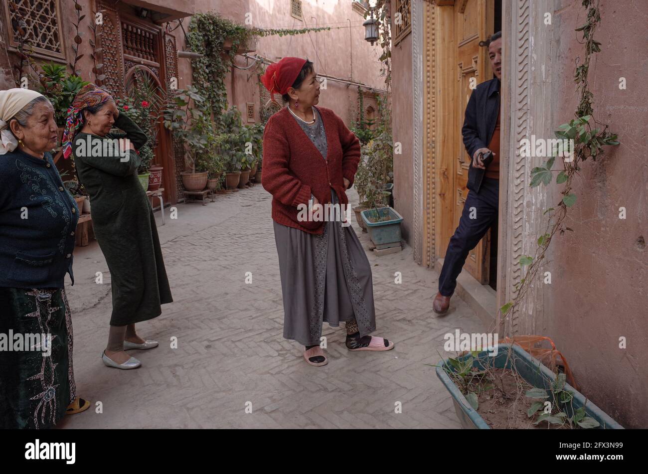 · 3 women of the Uygur ethnic group confronting a man leaving a house. Kashgar People's Republic of China 2019 Stock Photo
