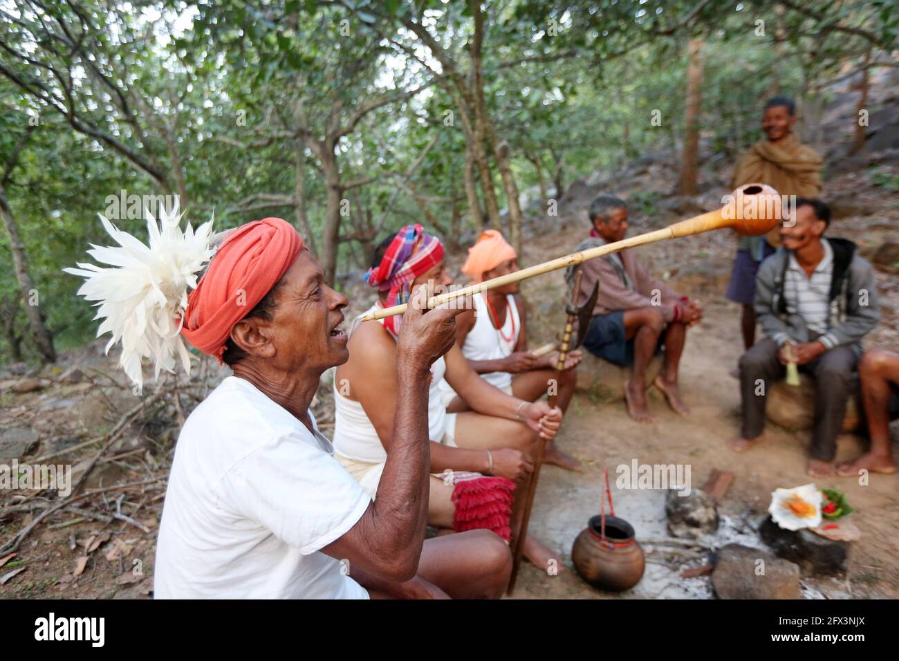 LANJIA SAORA TRIBE - Men gather in a circle drinking tadi or toddy a local wine from a large pot set over the fire. They use Jeri pipe made of dry gou Stock Photo