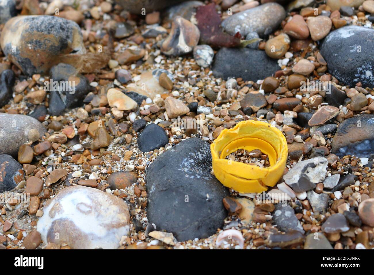 A yellow plastic bottle top on the beach Stock Photo