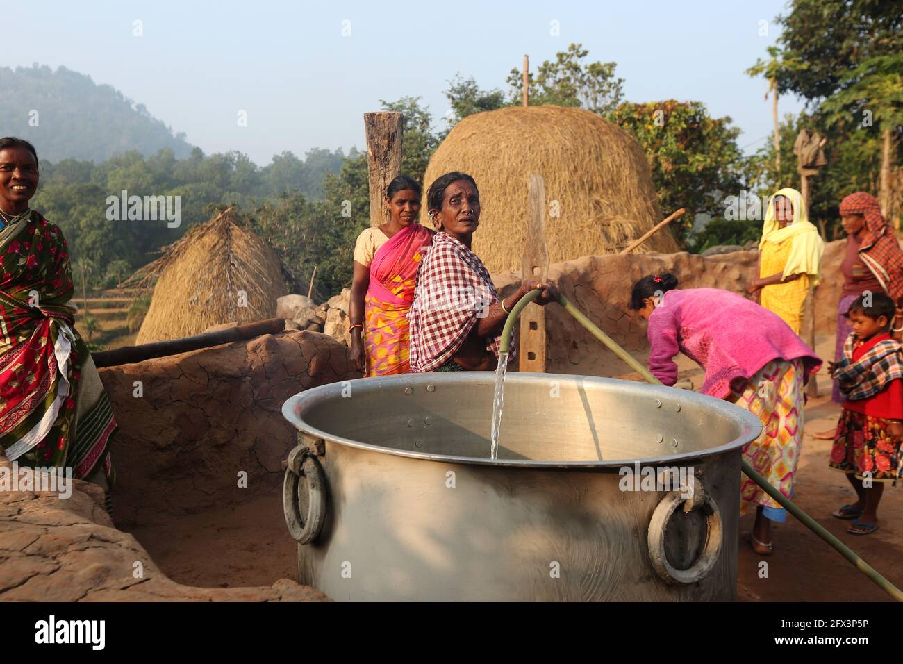 LANJIA SAORA TRIBE - Tribal woman pouring water in a big vessel using plastic pipe. This picture was clicked in Puttasingh tribal village of Odisha Stock Photo
