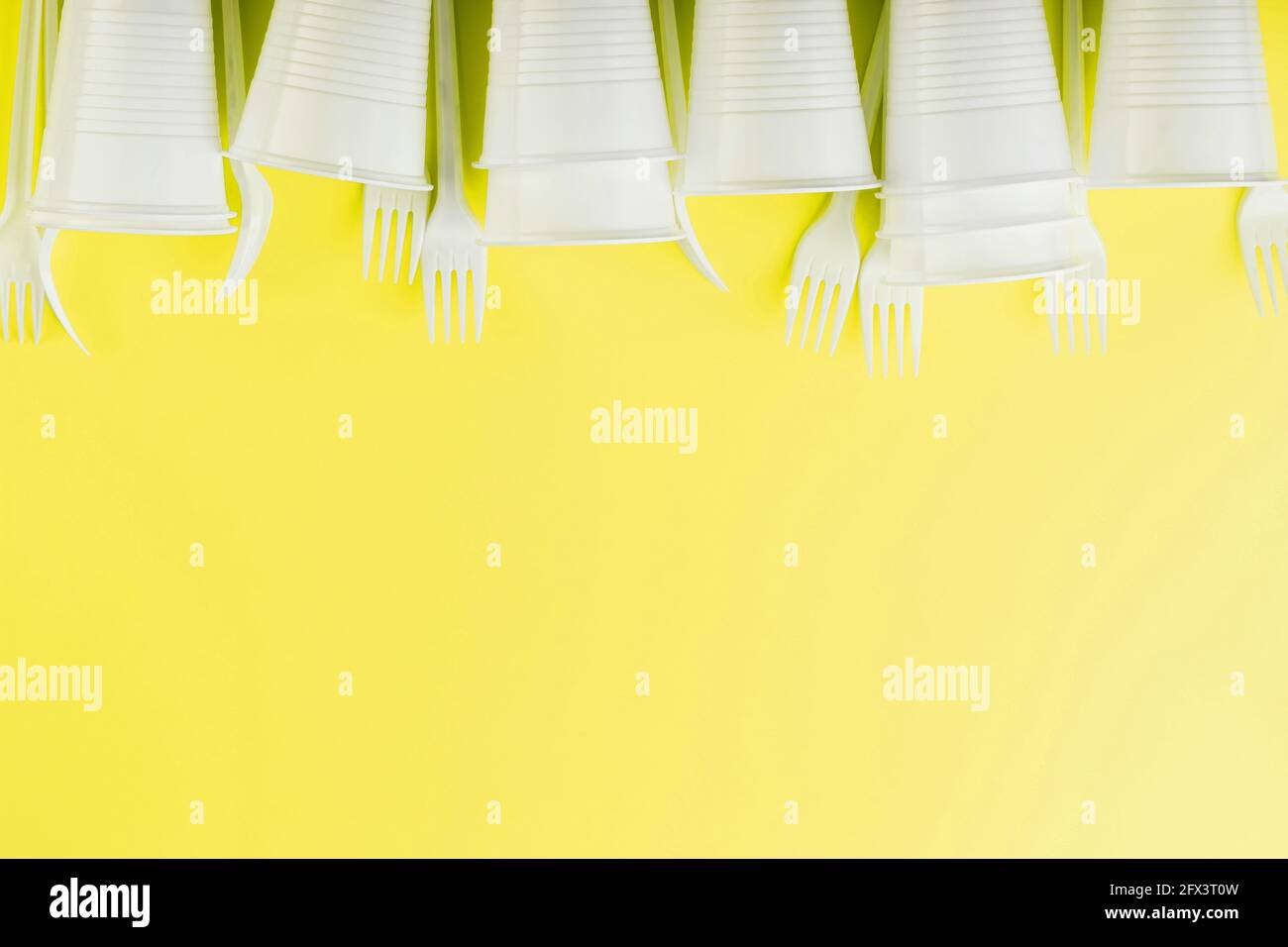 Plastic tableware on a yellow background with free space. Disposable tableware Stock Photo