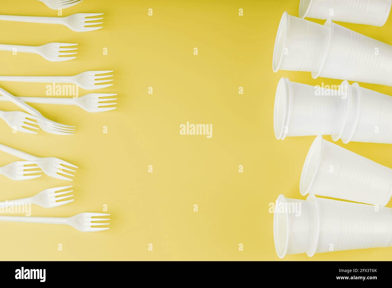 Plastic tableware on a yellow background with free space. Disposable tableware Stock Photo